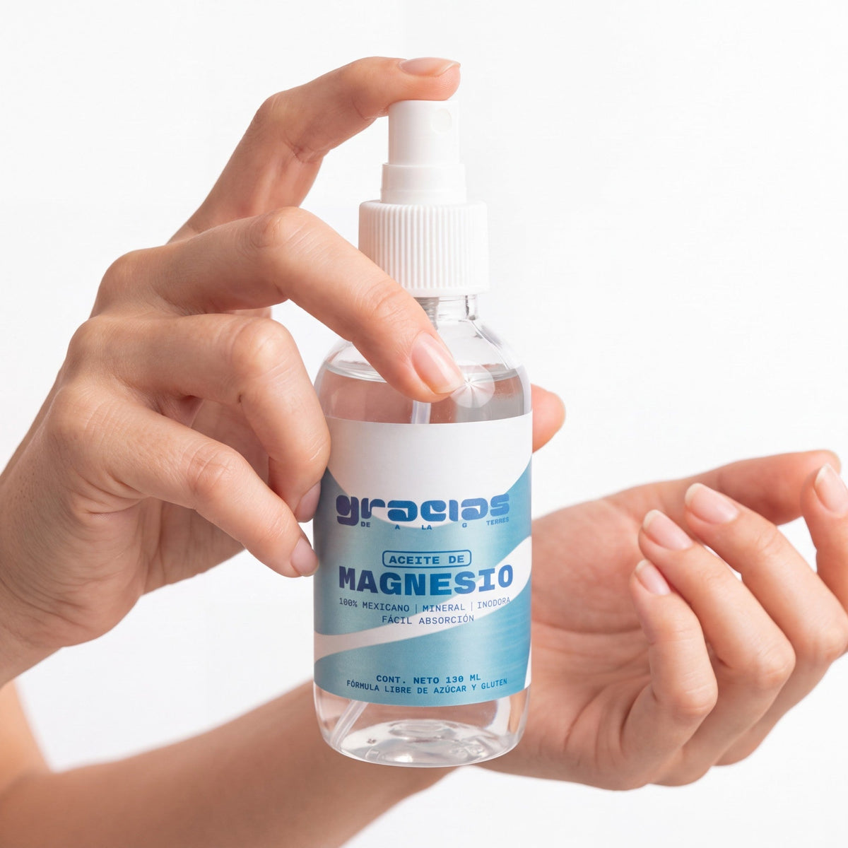 Manos sosteniendo un spray de Aceite de Magnesio Gracias de la Tierra de 130 ml para alivio muscular y relajación.